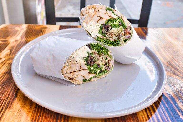 Two burritos on a plate on a wooden table.