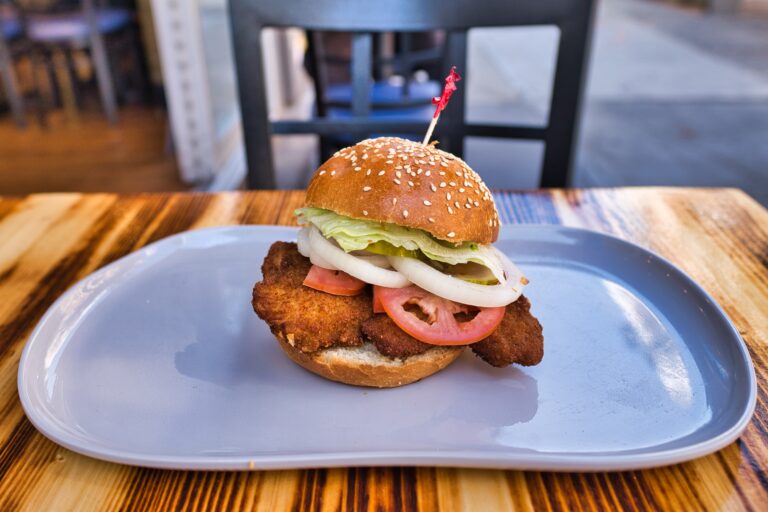A chicken sandwich is sitting on a plate on a table.