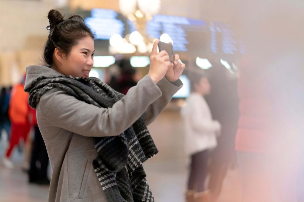 A woman is taking a picture with her cell phone.