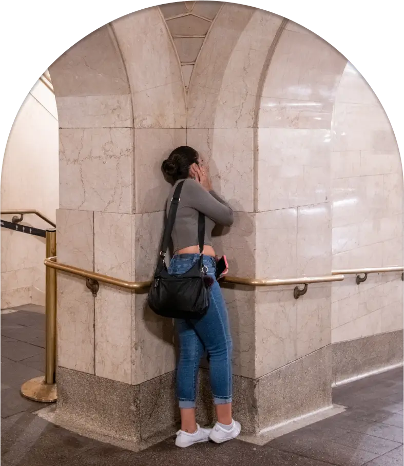 A woman leaning against a wall in a subway station.