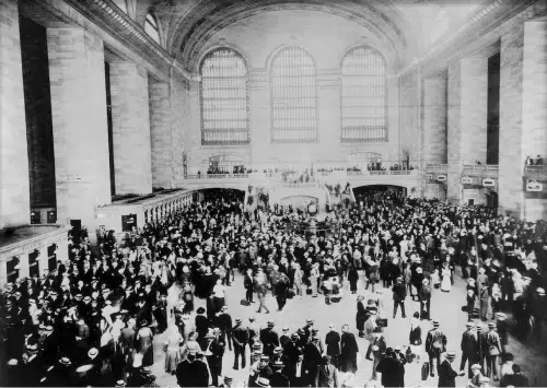 A black and white photo of a crowd at a train station.