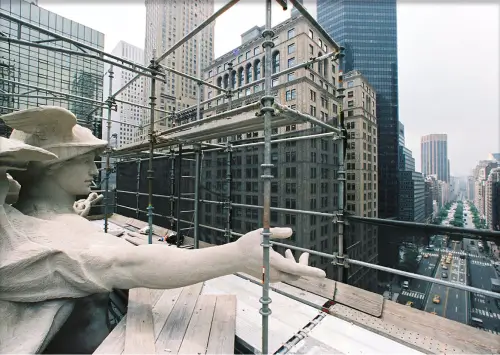 A statue with scaffolding on top of a building.