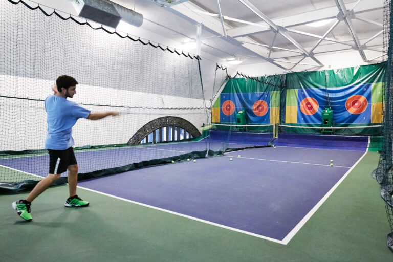 A man hitting a tennis ball in an indoor court.