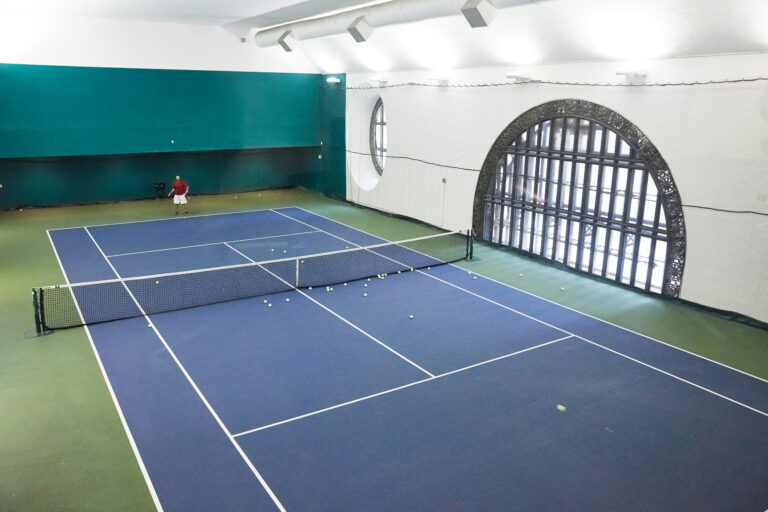 A tennis court in a large indoor space.