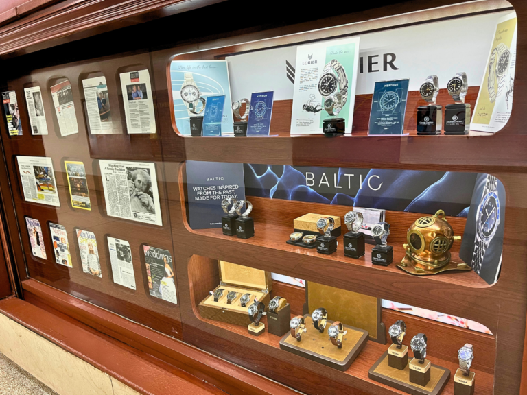 A display of watches and other items in a glass case.