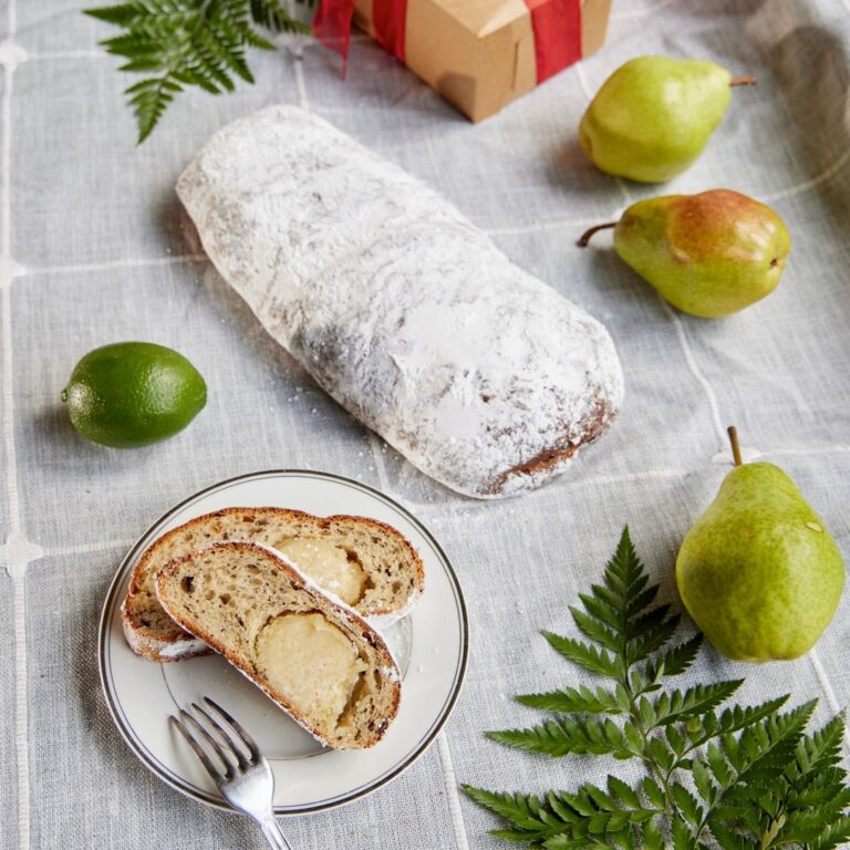 A plate of bread and pears on a table next to a gift.
