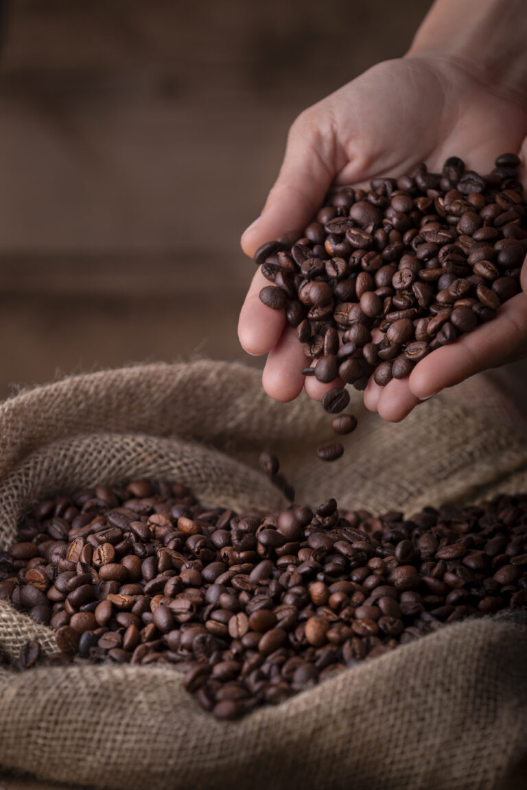 A hand is holding coffee beans in a sack.