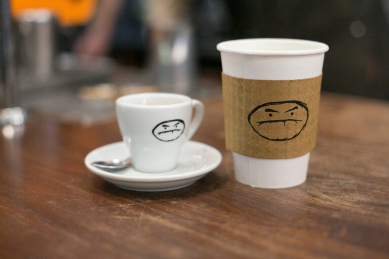 A cup of coffee with a smiley face on it.