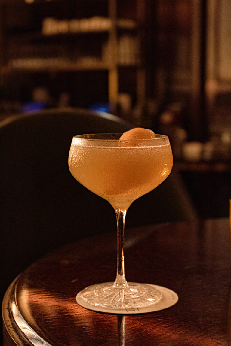 A cocktail is sitting on top of a wooden table.