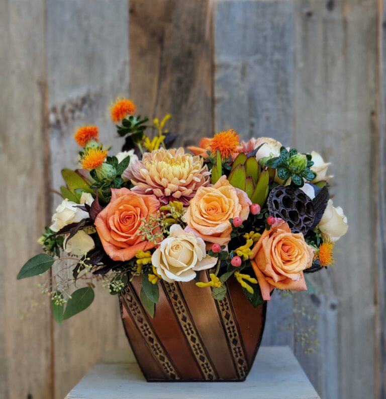 A bouquet of orange and brown flowers in a wooden vase.