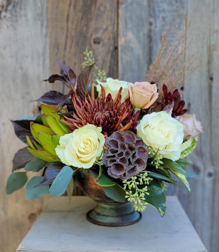 An arrangement of flowers in a vase on top of a wooden table.