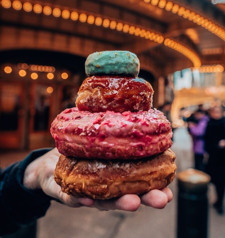 A person holding a stack of donuts in front of a theater.