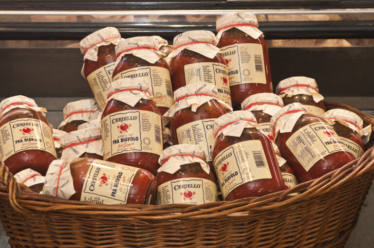 A wicker basket filled with jars of sauce.