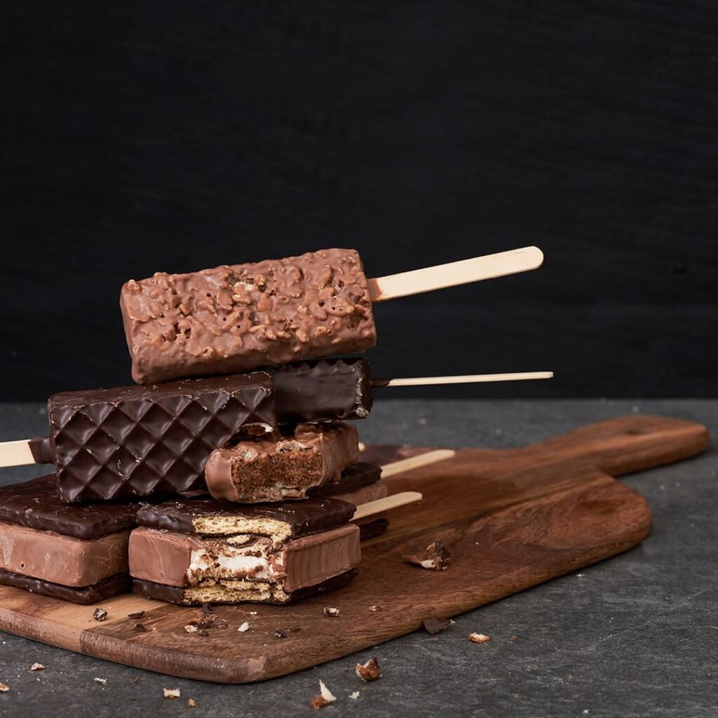 Chocolate popsicles on a wooden cutting board.