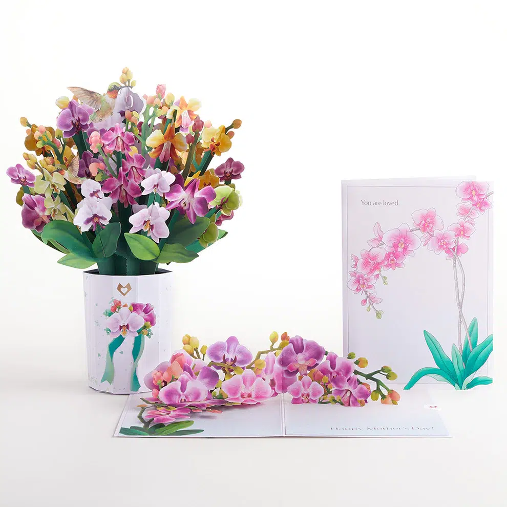 A greeting card with a vase of orchids and a card next to it.