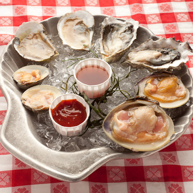 A platter of oysters on ice with ketchup and ketchup.