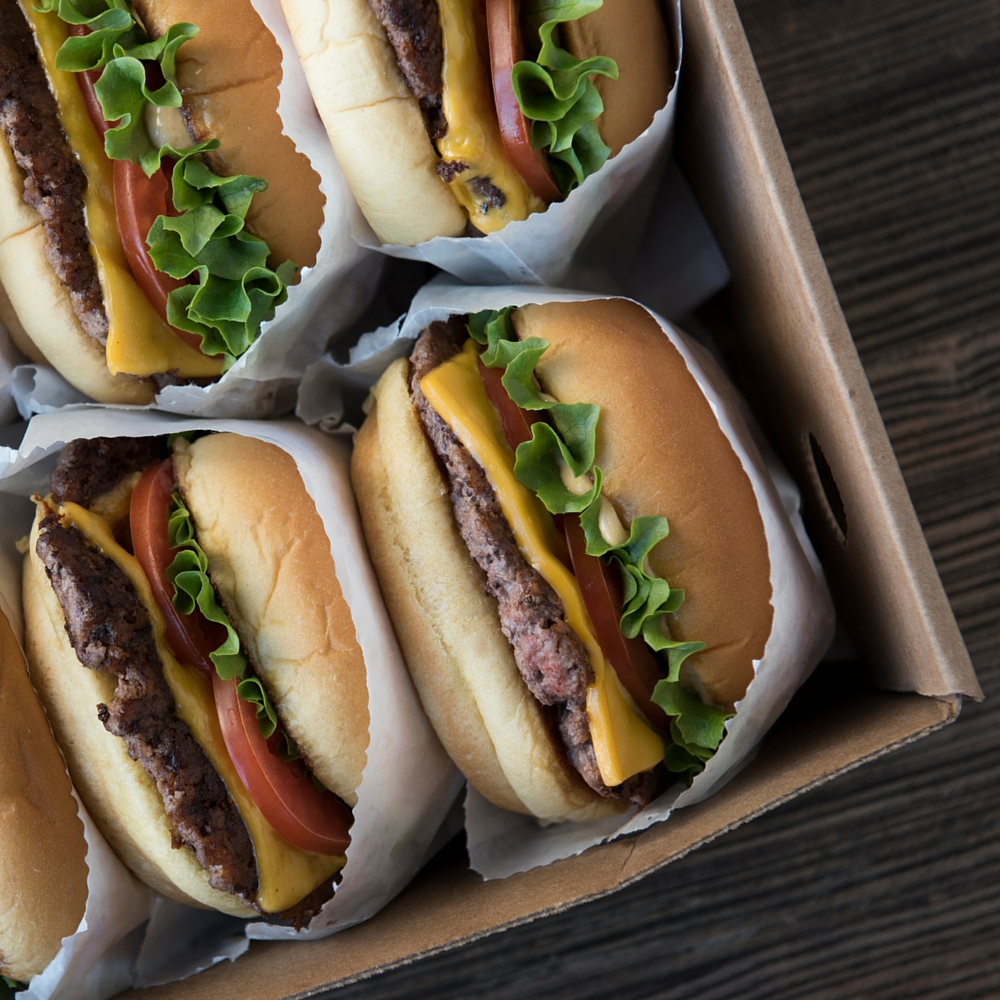 Four hamburgers in a cardboard box.