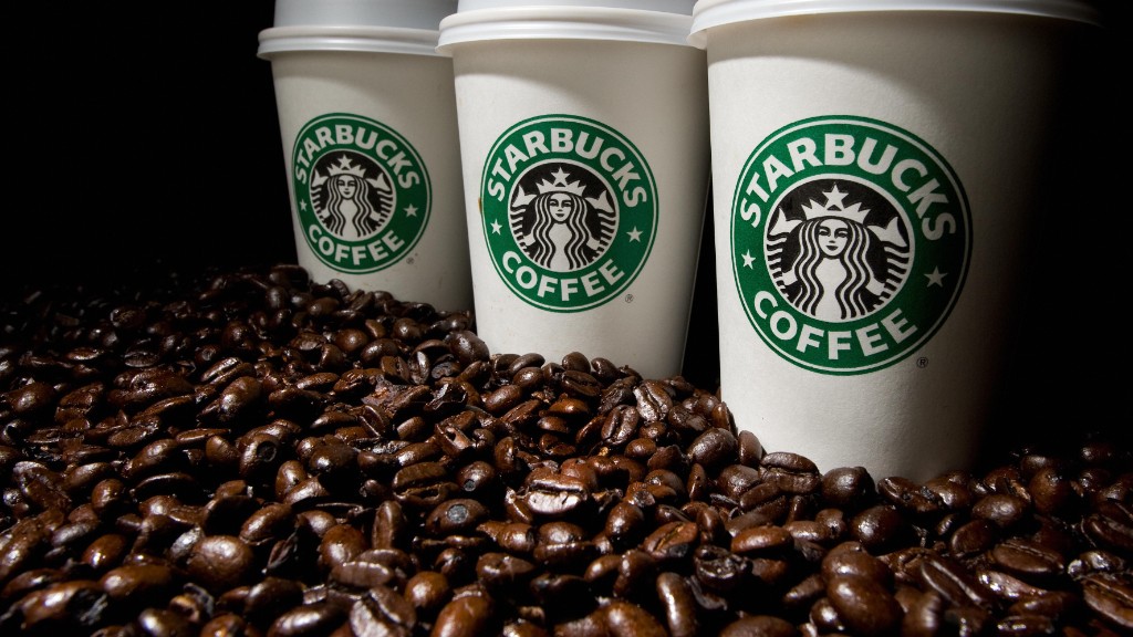 Three starbucks coffee cups surrounded by coffee beans.