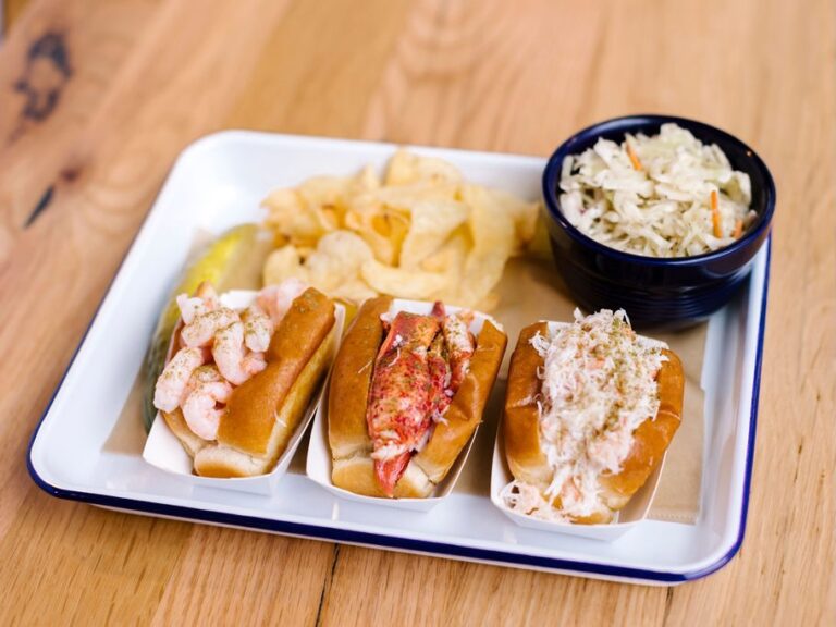 Four hot dogs with coleslaw and potato chips on a plate.