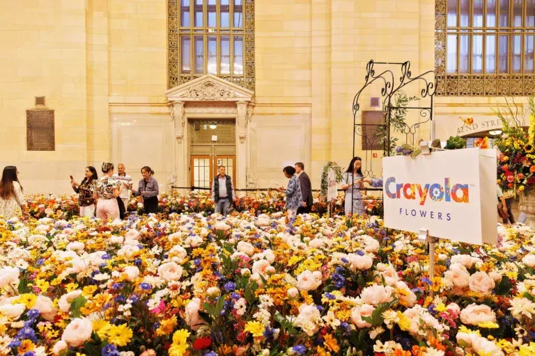A large group of people standing in front of a large flower arrangement.