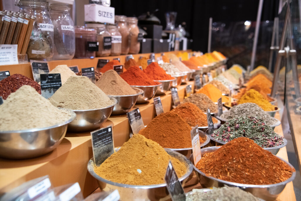 A display of spices in bowls on a shelf.