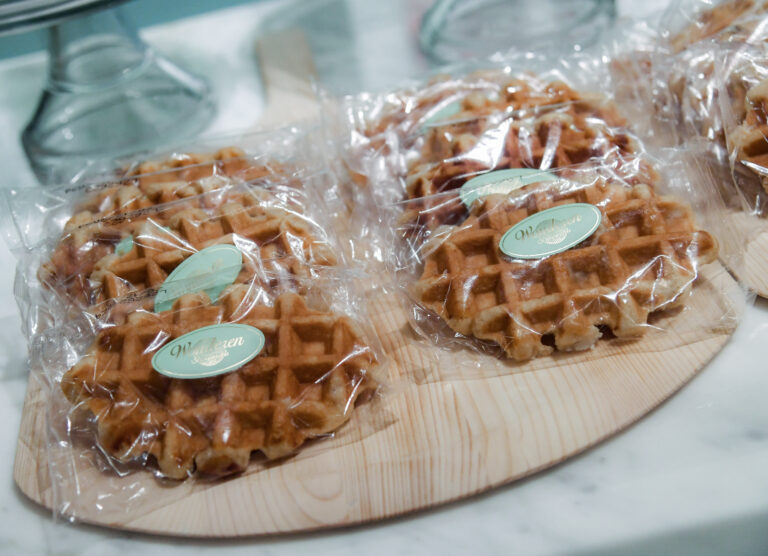 Waffles are sitting on a wooden cutting board.